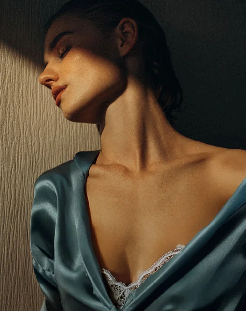 Profile of a woman in a blue silk robe with soft light hitting her face and neck.