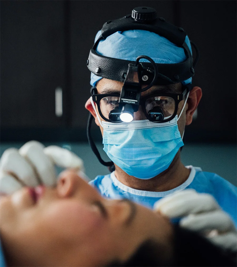 Dr. Haque wearing surgical loupes and a mask while treating a patient. - Procedures in Charlotte, NC