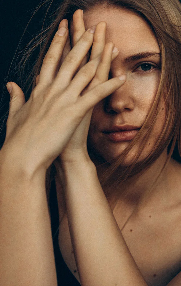A woman’s face partially obscured by her hands. - Hand Injuries in Charlotte, NC