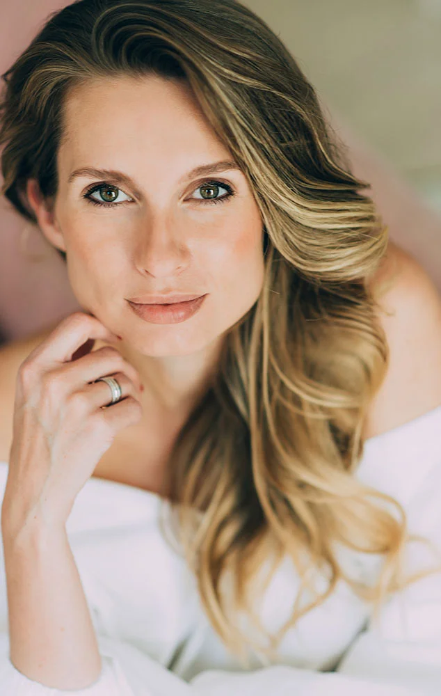 A woman touching her cheek while looking up and smiling slightly. - Skin Lesions Lipoma in Charlotte, NC